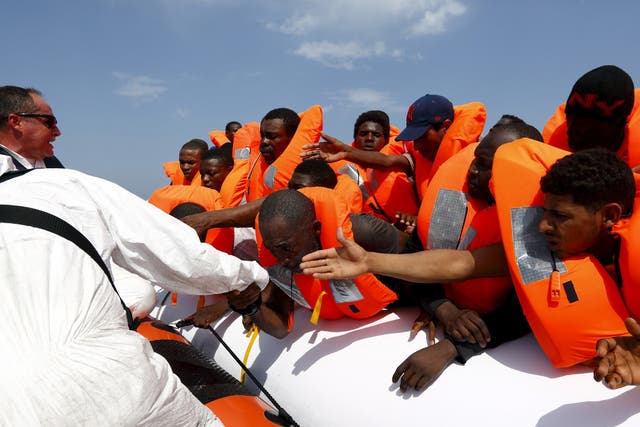 Migrants are helped to cross from their rubber dinghy to a Migrant Offshore Aid Station