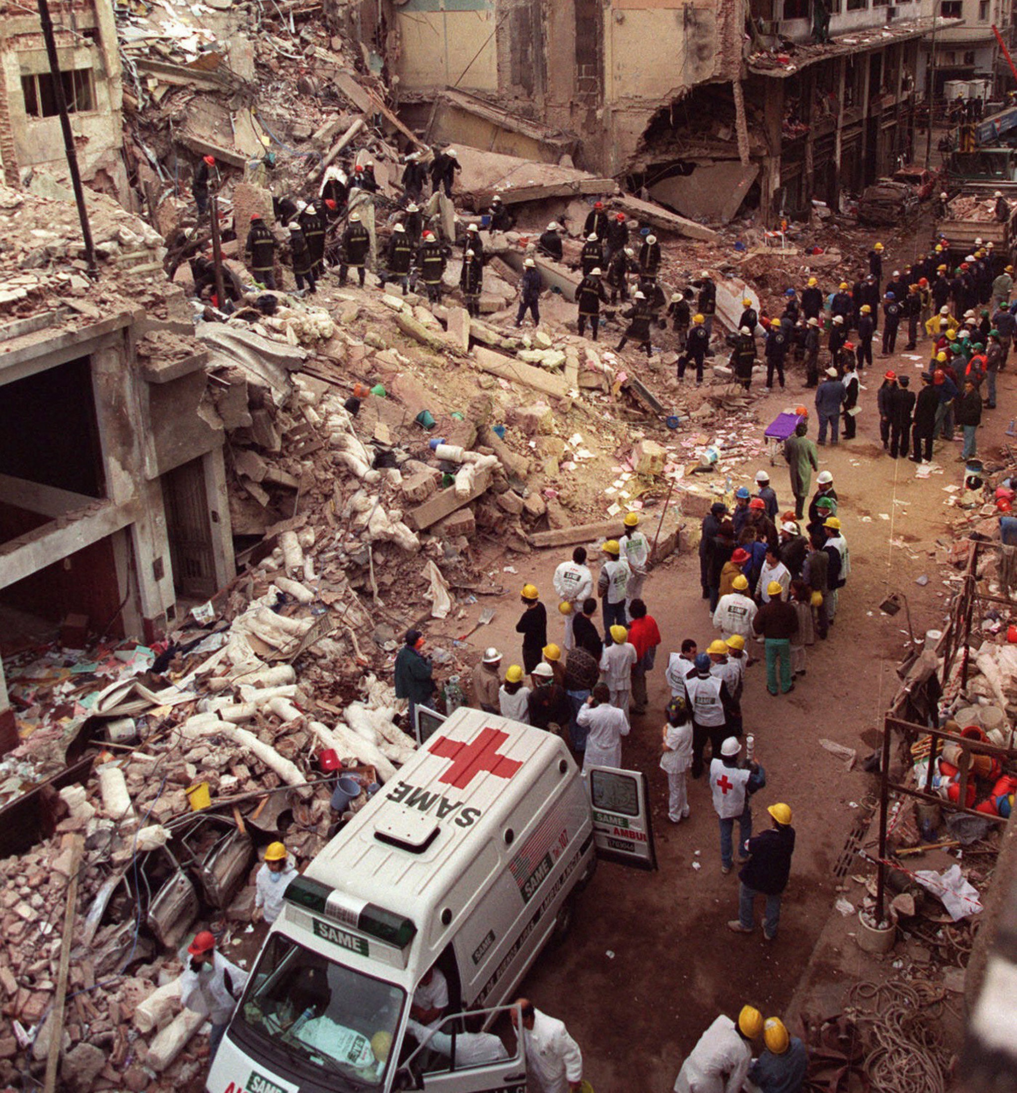 Firefighters and rescue workers search through the rubble of the Argentine-Israeli Mutual Association community center