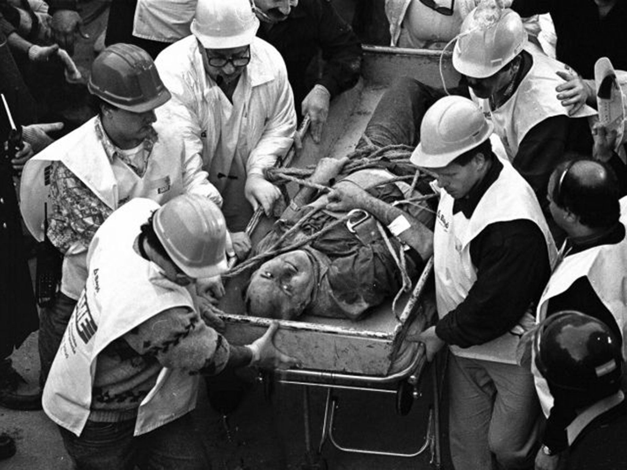 Firemen search as wounded people walk over the rubble left after a bomb exploded at the Argentinian Israelite Mutual Association (AMIA in Spanish) in Buenos Aires, 18 July 1994