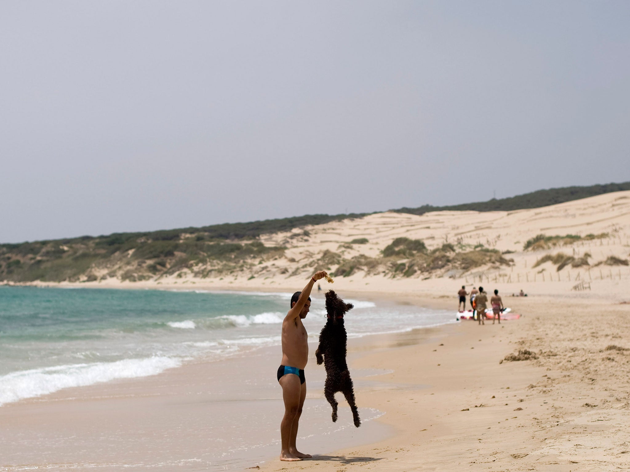 A man plays with his dog at the Valdevaqueros beach in Tarifa, near Cadiz