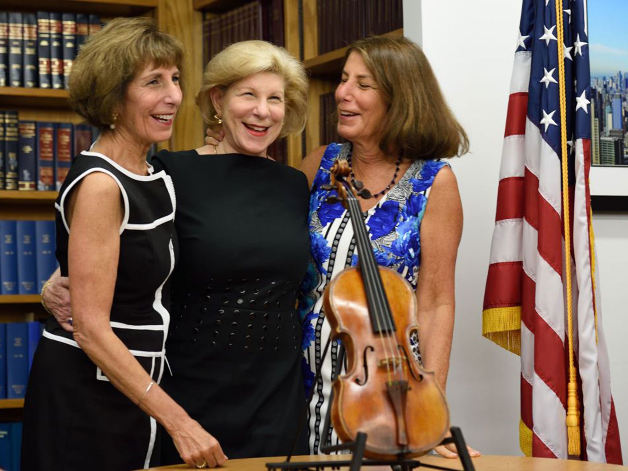 Nina (C), Jill, and Amy Totenberg (R) pose with the stolen Stradivarius violin belonging to the late renowned violinist Roman Totenberg