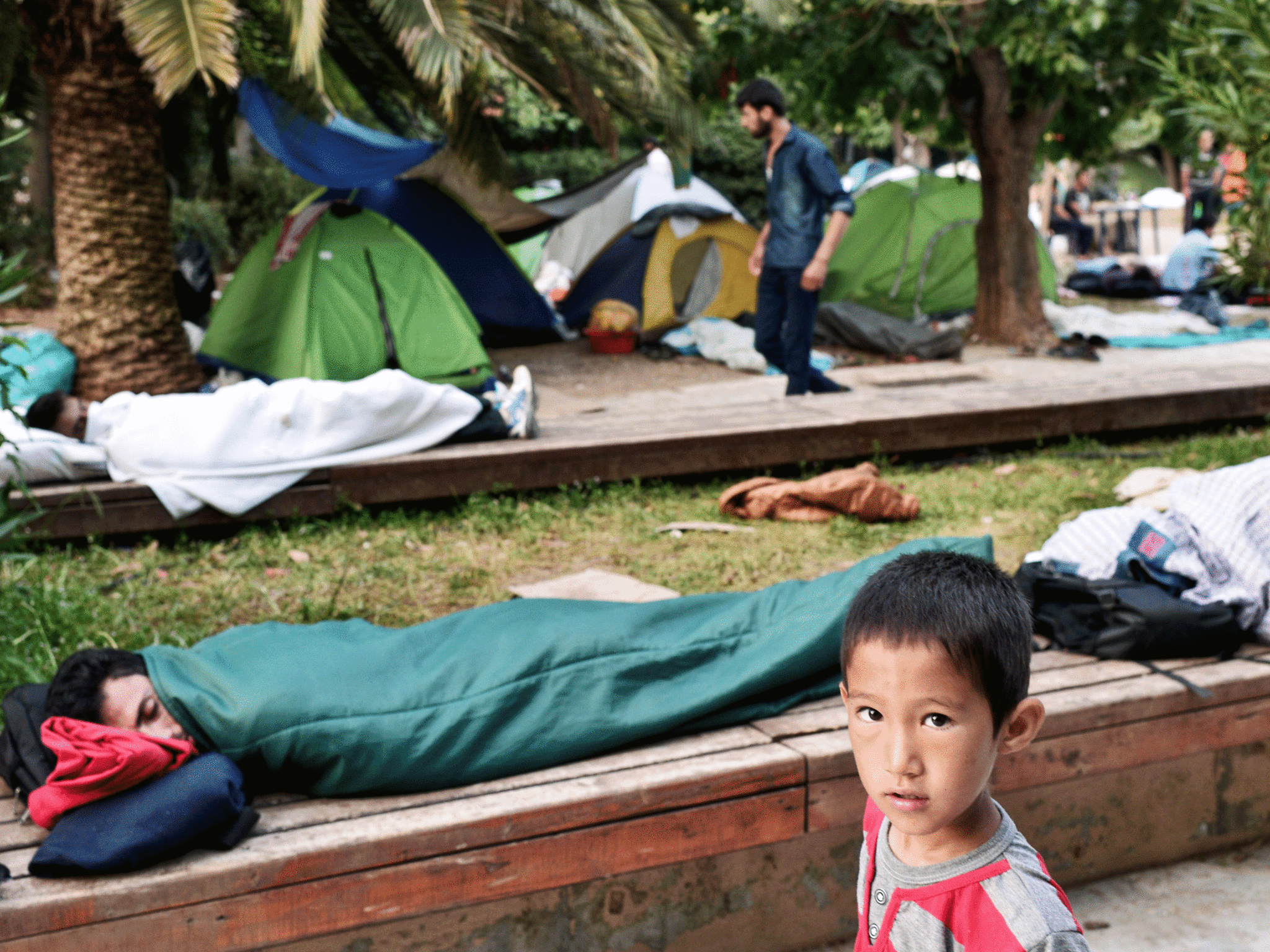 Migrants sleep in a park in central Athens