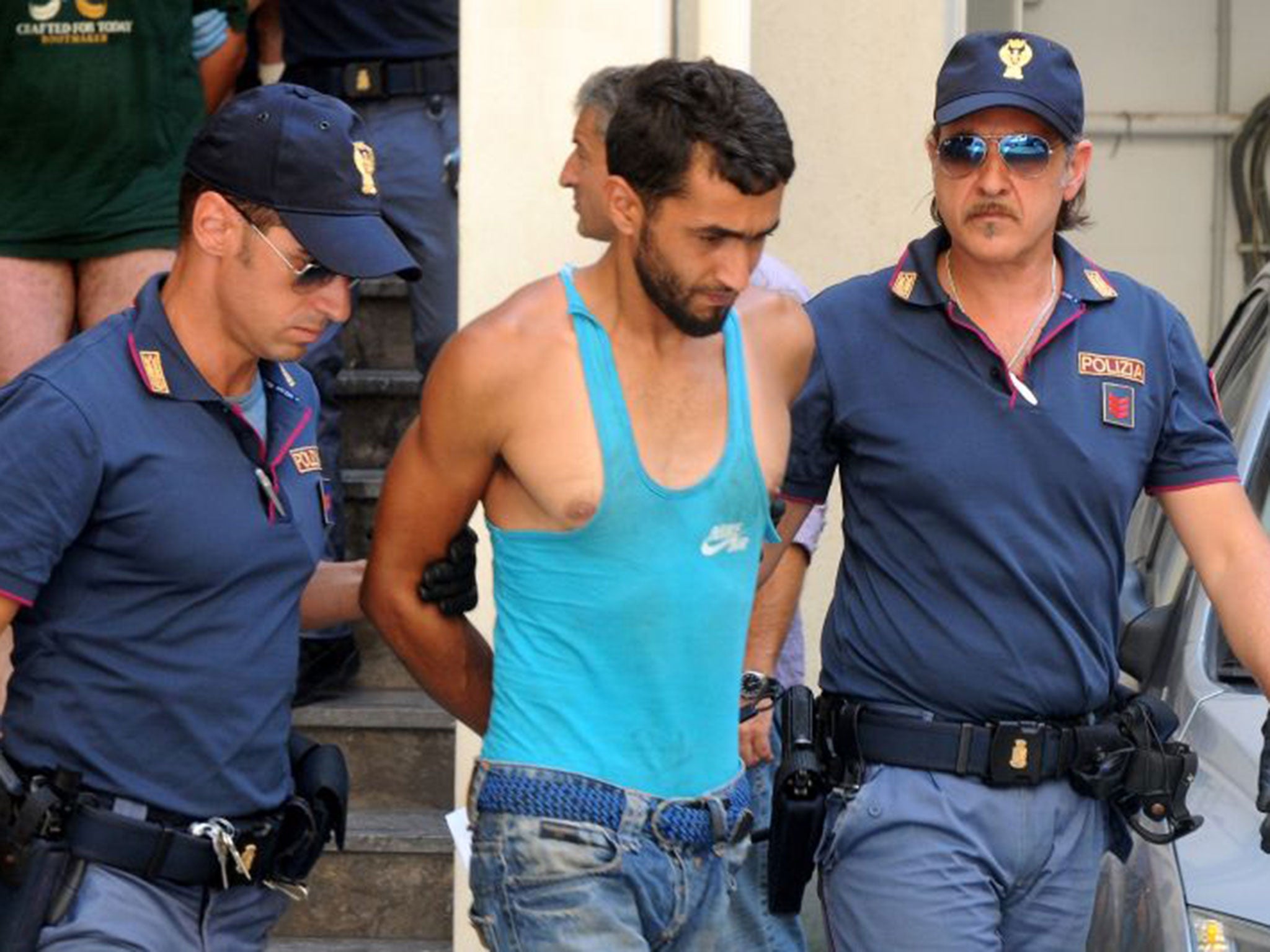 Italian police officers take in custody Imad Busadia, center, one of the five alleged smugglers who were detained on Thursday