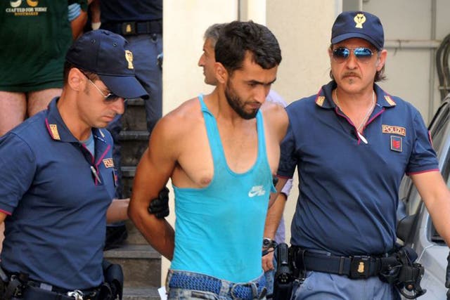 Italian police officers take in custody Imad Busadia, center, one of the five alleged smugglers who were detained on Thursday 