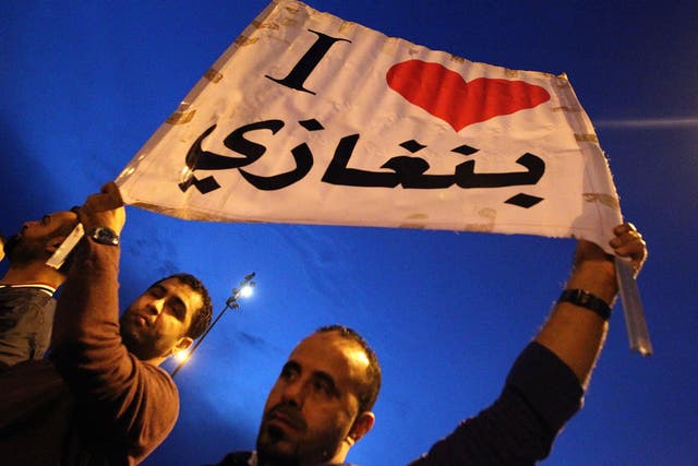 Protesters raise up a placard reading in Arabic "I love Benghazi" during a demonstration in front of the Tibesti hotel in support of the Libyan Army and Police