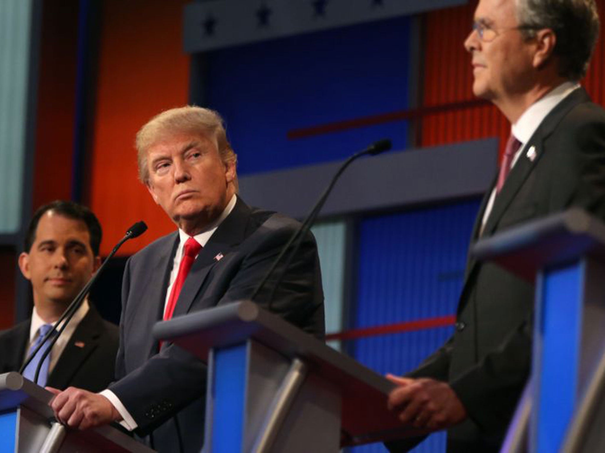 Republican presidential candidate Donald Trump looks toward Jeb Bush, right, as Scott Walker watches during the first Republican presidential debate