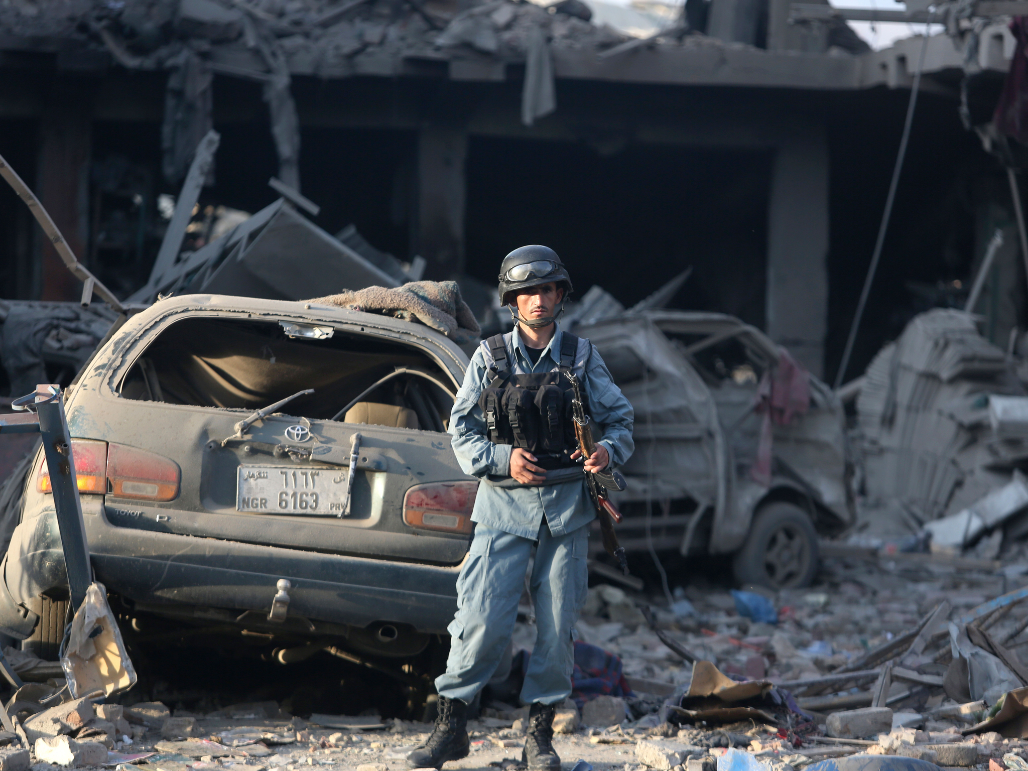 An Afghan policeman stands guard at the site of a truck bomb attack