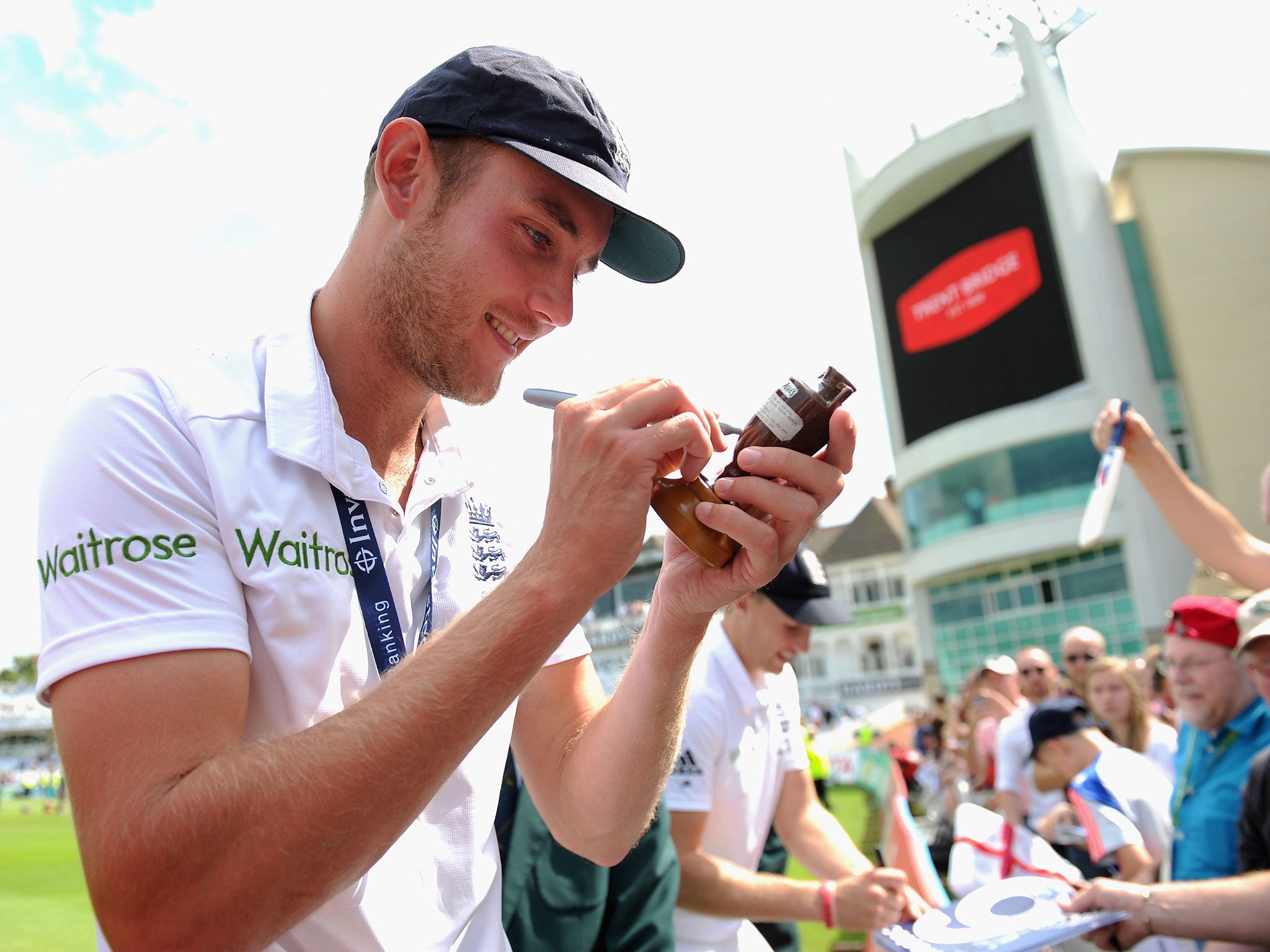 Stuart Broad of England is handed a replica ashes urn to sign