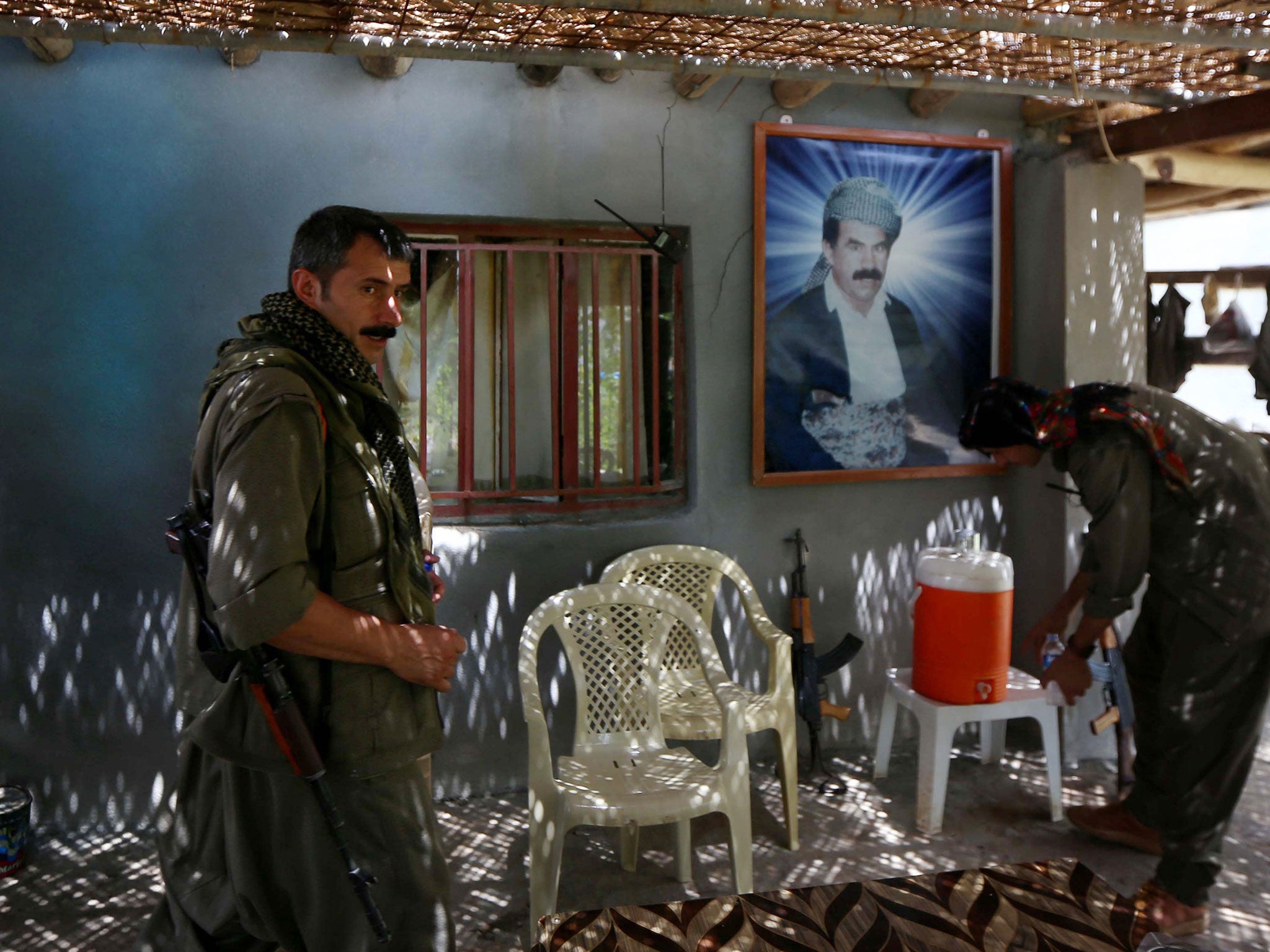 Members of the Kurdistan Workers' Party (PKK) rest in front of a portrait of jailed Kurdish rebel chief Abdullah Ocalan at a camp on July 29, 2015
