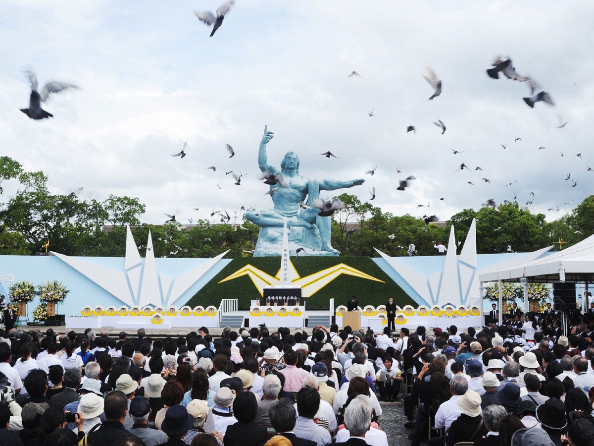 Pigeons fly around the peace statue during memorial service