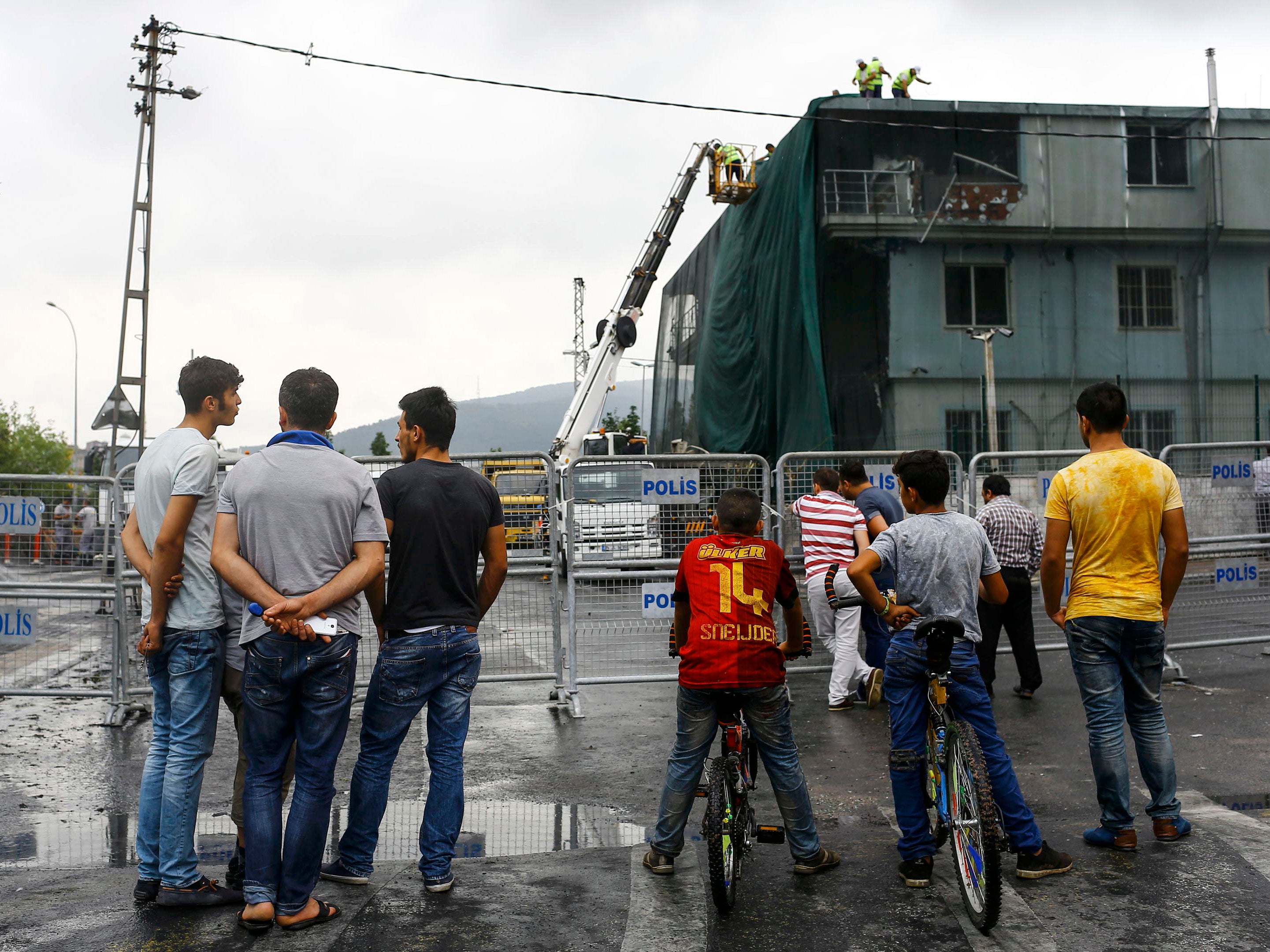 People look at a police station which was damaged during an attack in Istanbul, Turkey August 10, 2015.