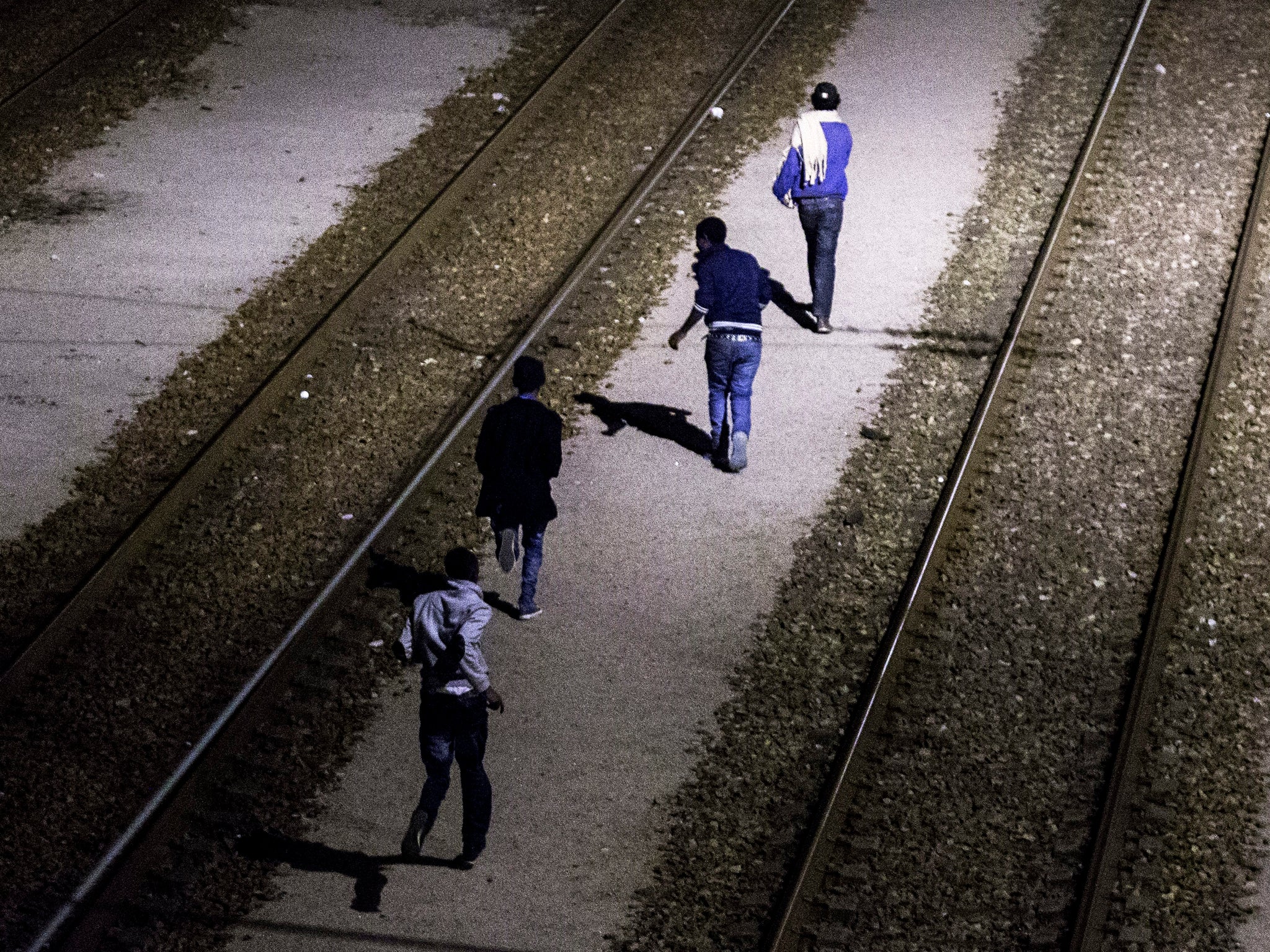 Migrants run on the shuttle tracks after they succeeded to jump over the fences and avoid the French patrols on the outskirts of Calais.