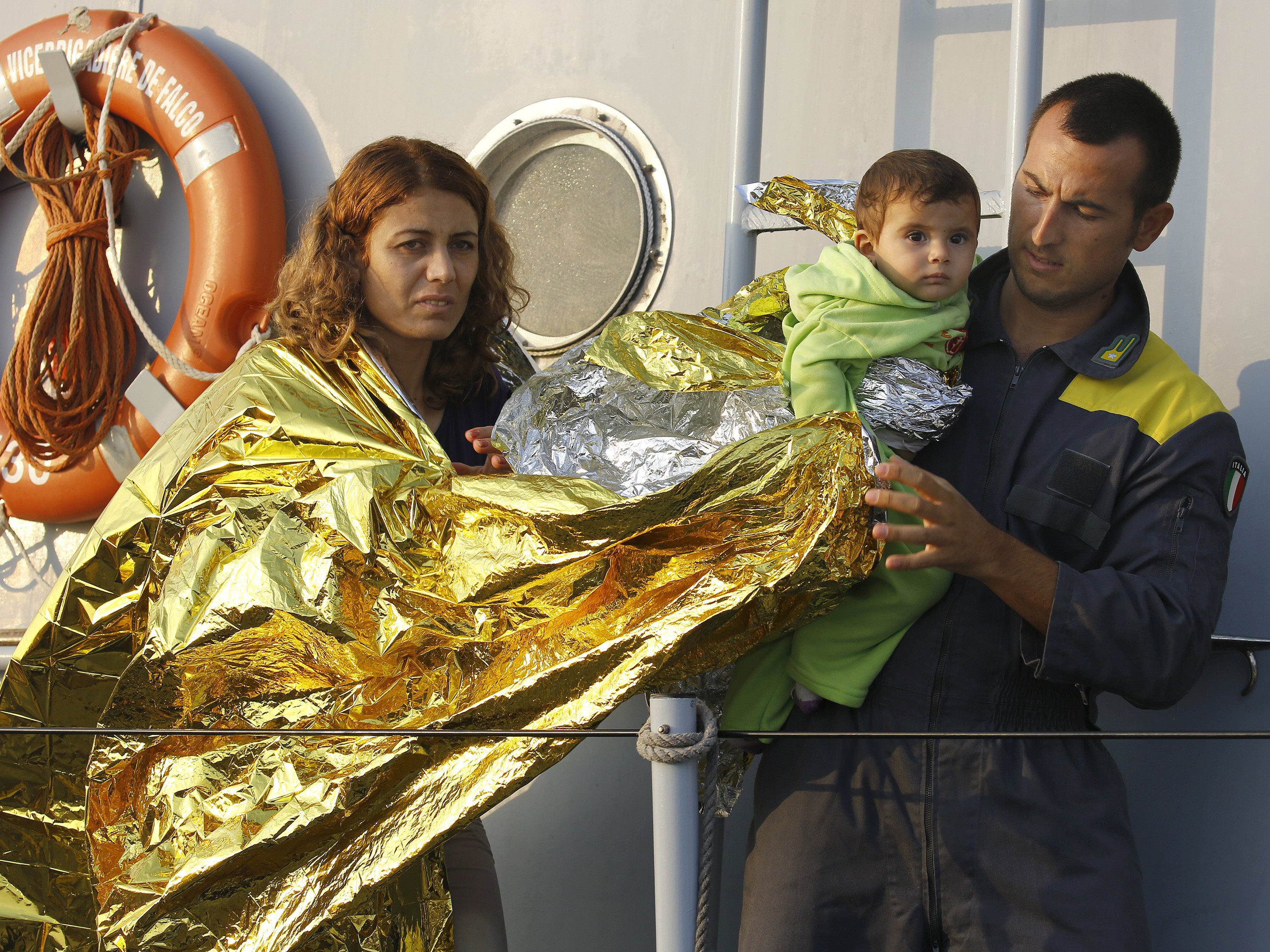 An Italian coast guard officer helps Syrian refugees from Kobani in the port of Kos following a rescue mission off the Greek island.