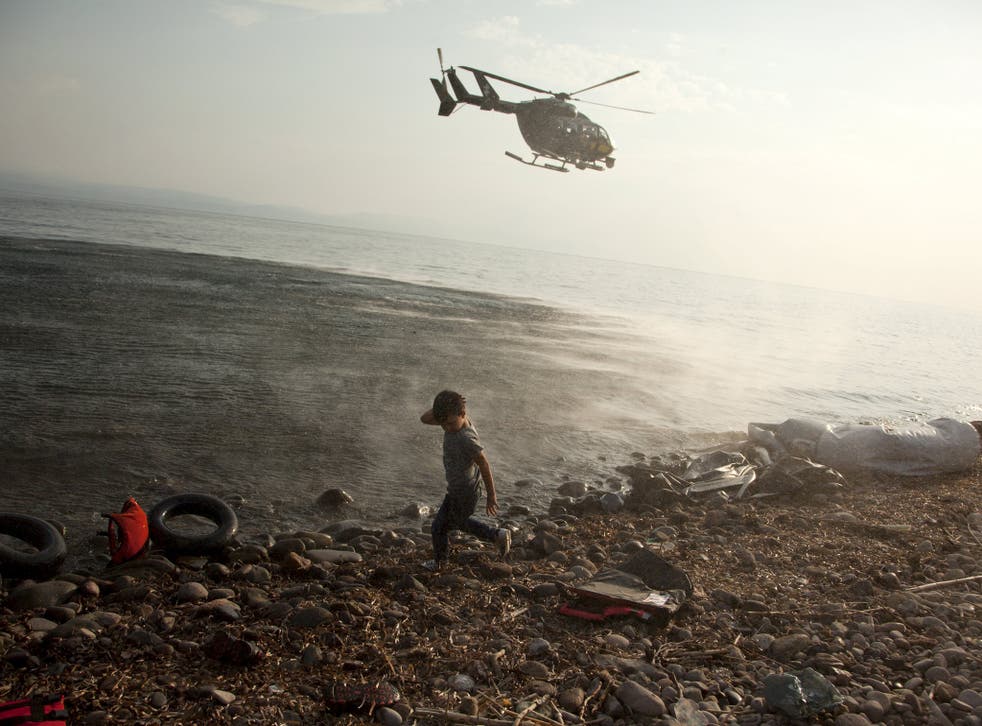 A Frontex helicopter patrols over a Syrian child that has just arrived at a beach at the Greek island of Lesvos, August 10, 2015