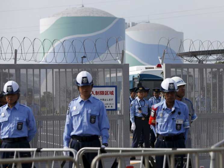 Police officers and security personnel stand guard at an entrance of Kyushu Electric Power's Sendai nuclear power station