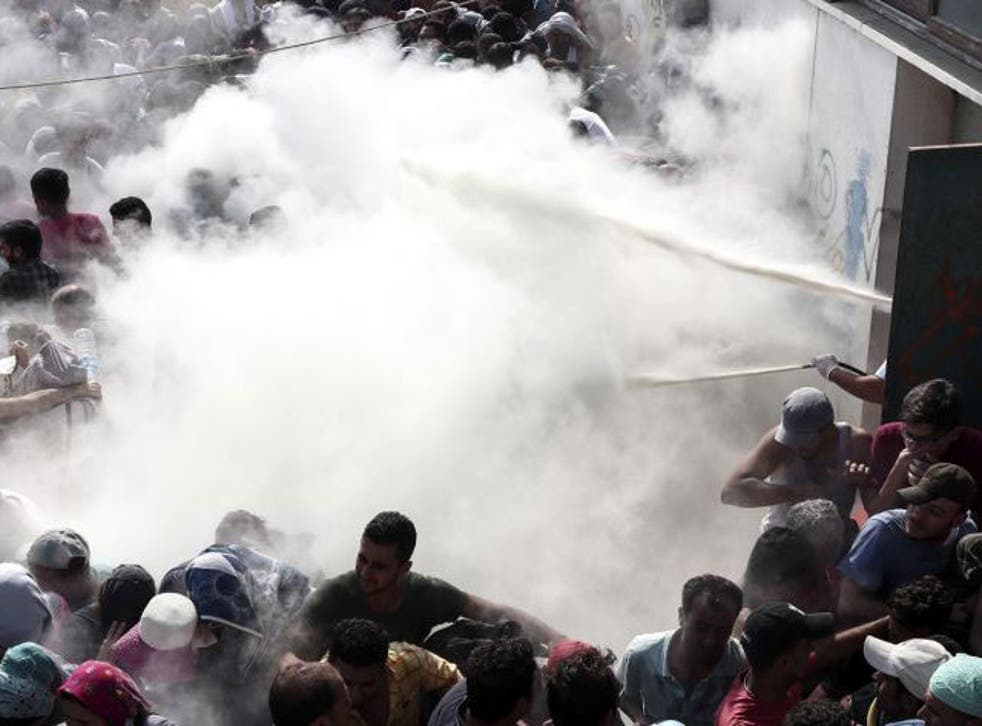 Police try to disperse crowds outside the Kos stadium by spraying them with fire extinguishers
