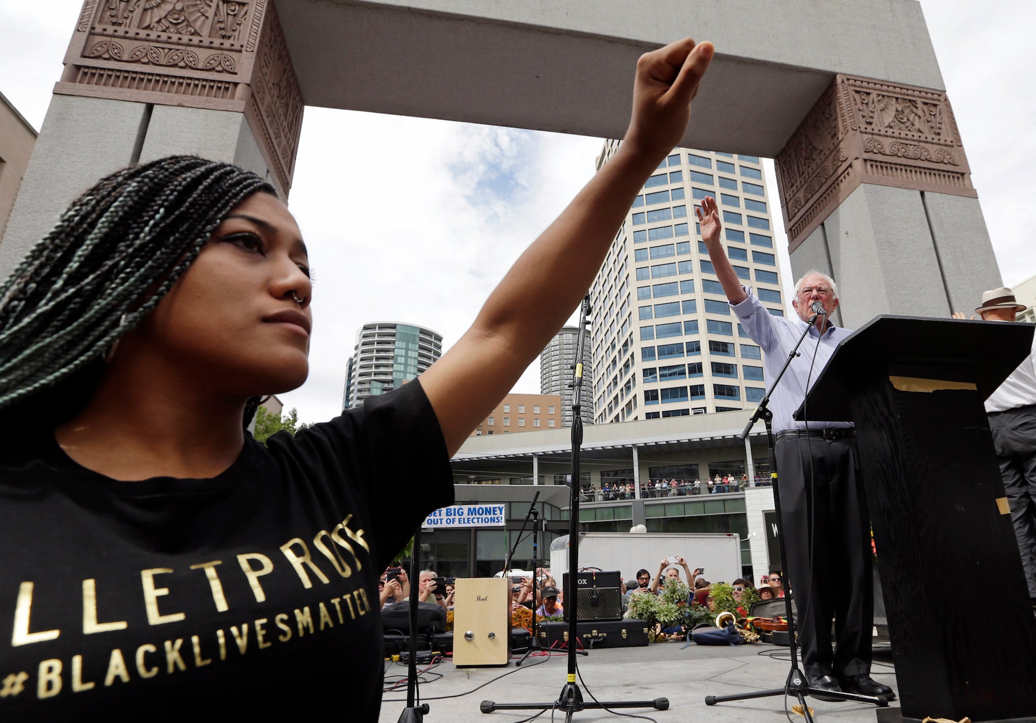 Mara Jacqueline Willaford, left, raises her fist as Bernie Sanders waves to greet the crowd before speaking at a rally on Saturday.