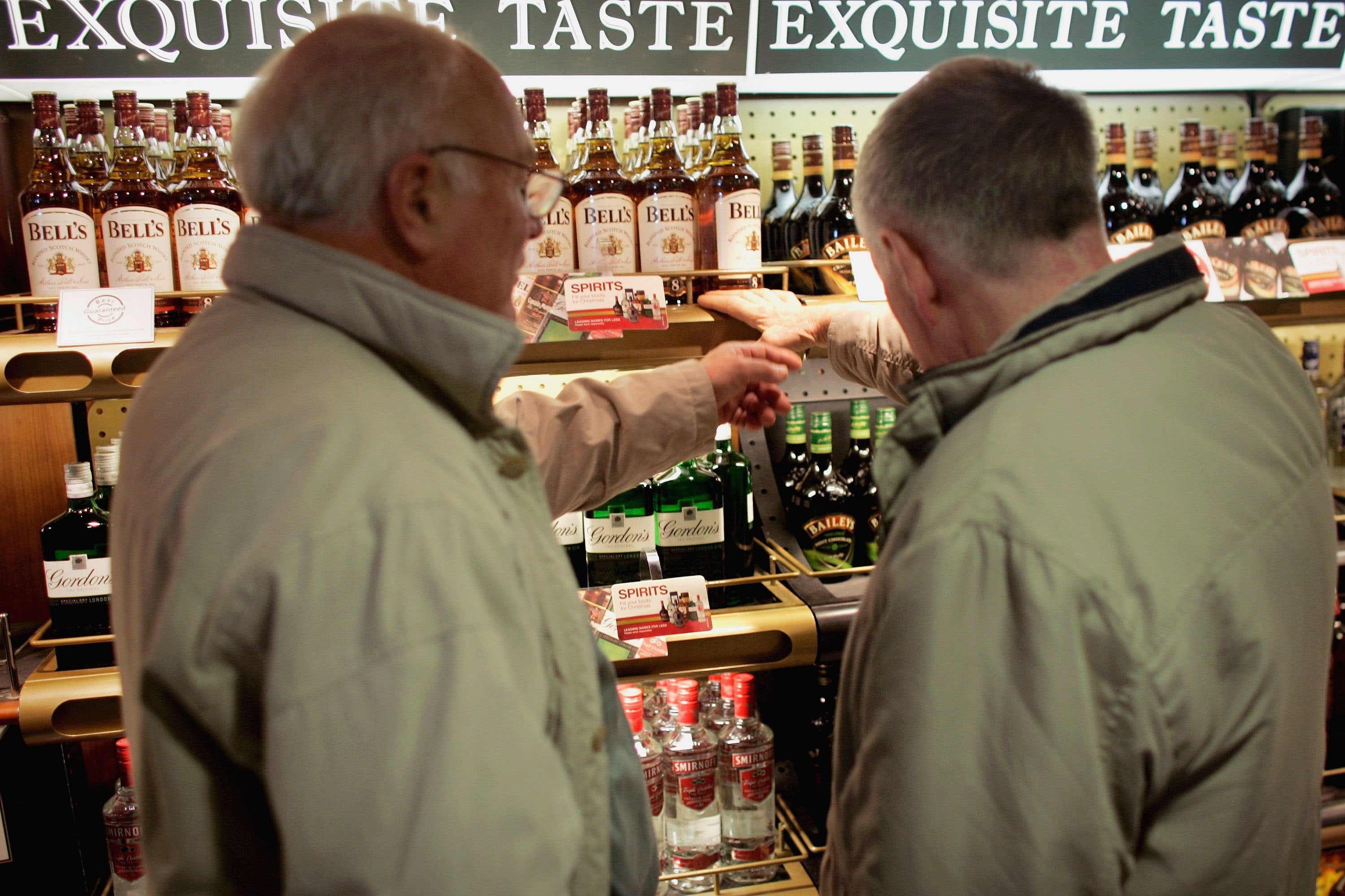 Two passengers discuss which spirits to buy at a duty free store