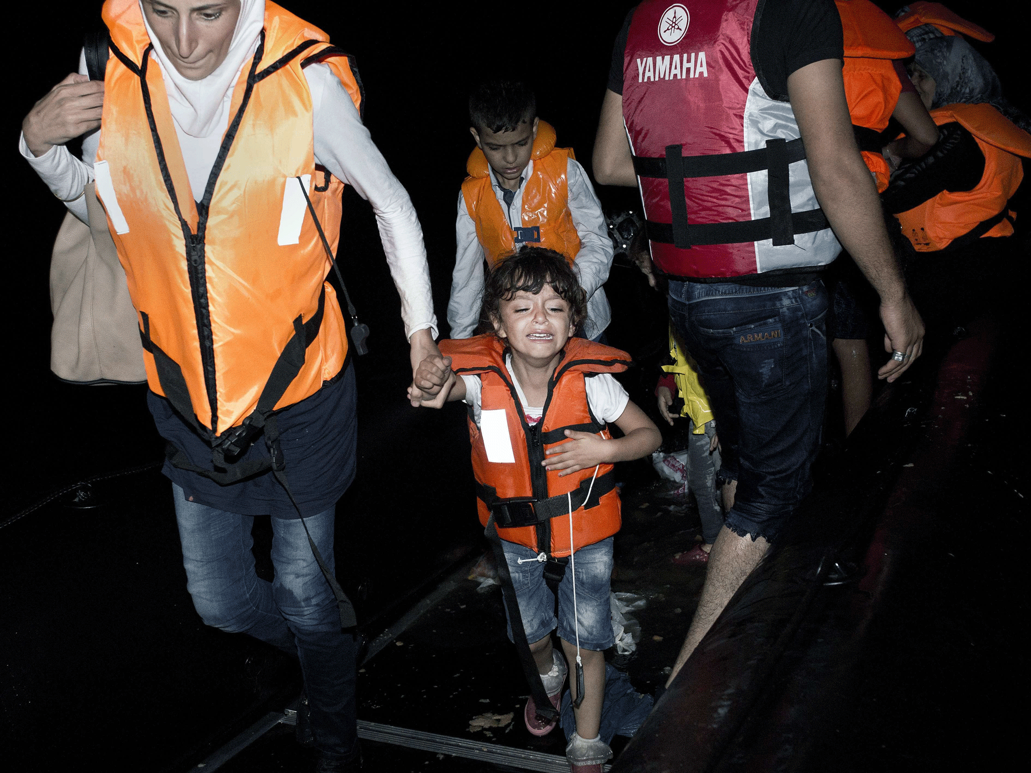 A young girl gets out of an inflatable boat while migrants arrive on a beach on the Greek island of Kos, after crossing a part of the Aegean Sea between Turkey and Greece, on August 12, 2015