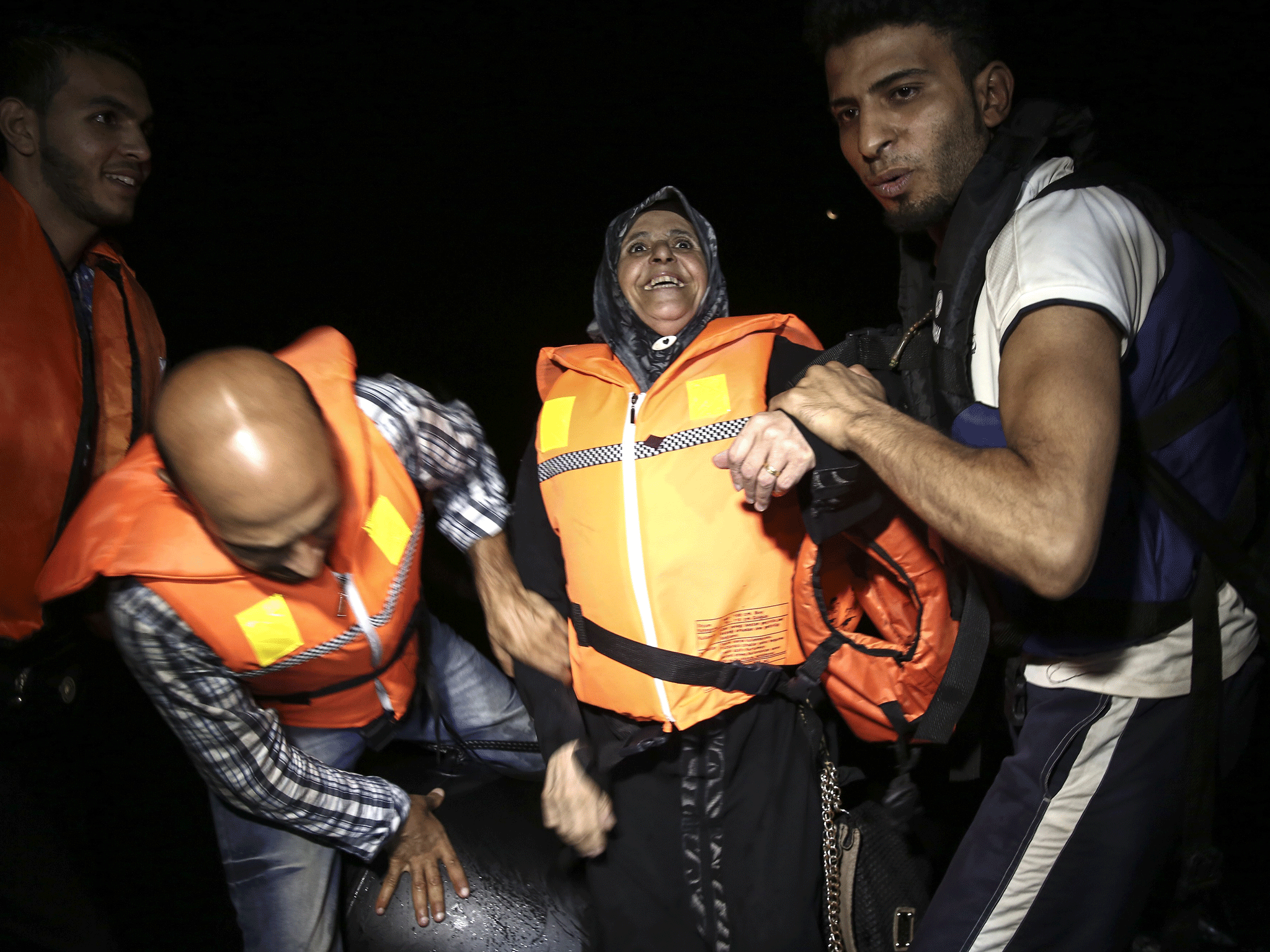 A migrant is helped out of a dinghy after crossing from Turkey to Kos