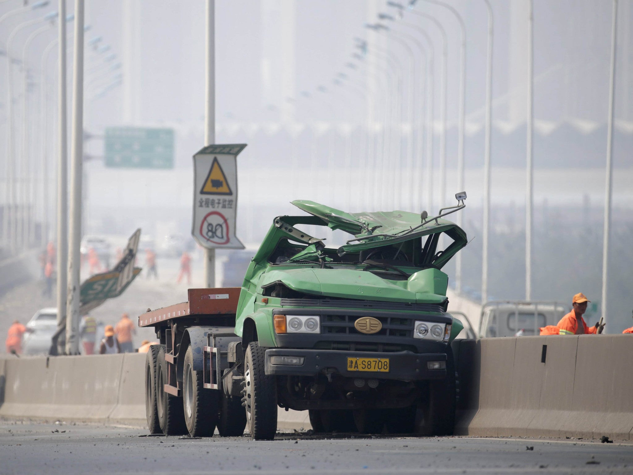 A damaged truck is seen on a highway near the site of the explosions at the Binhai new district in Tianjin