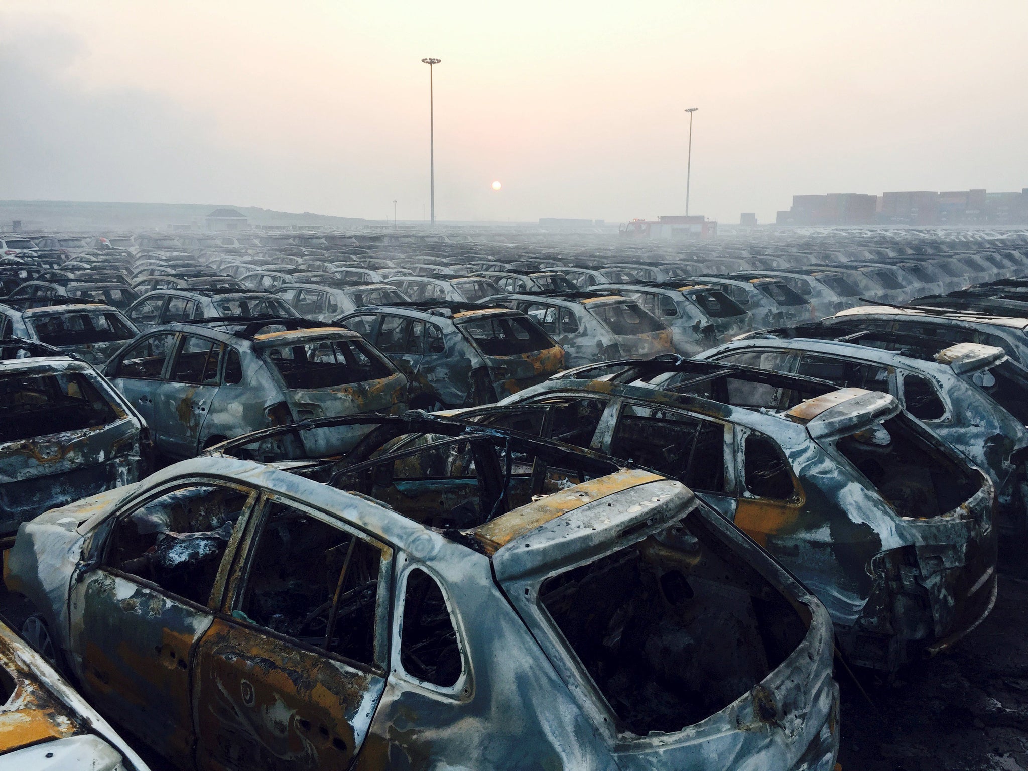 Damaged cars are seen near the site of explosions at the Binhai new district in Tianjin