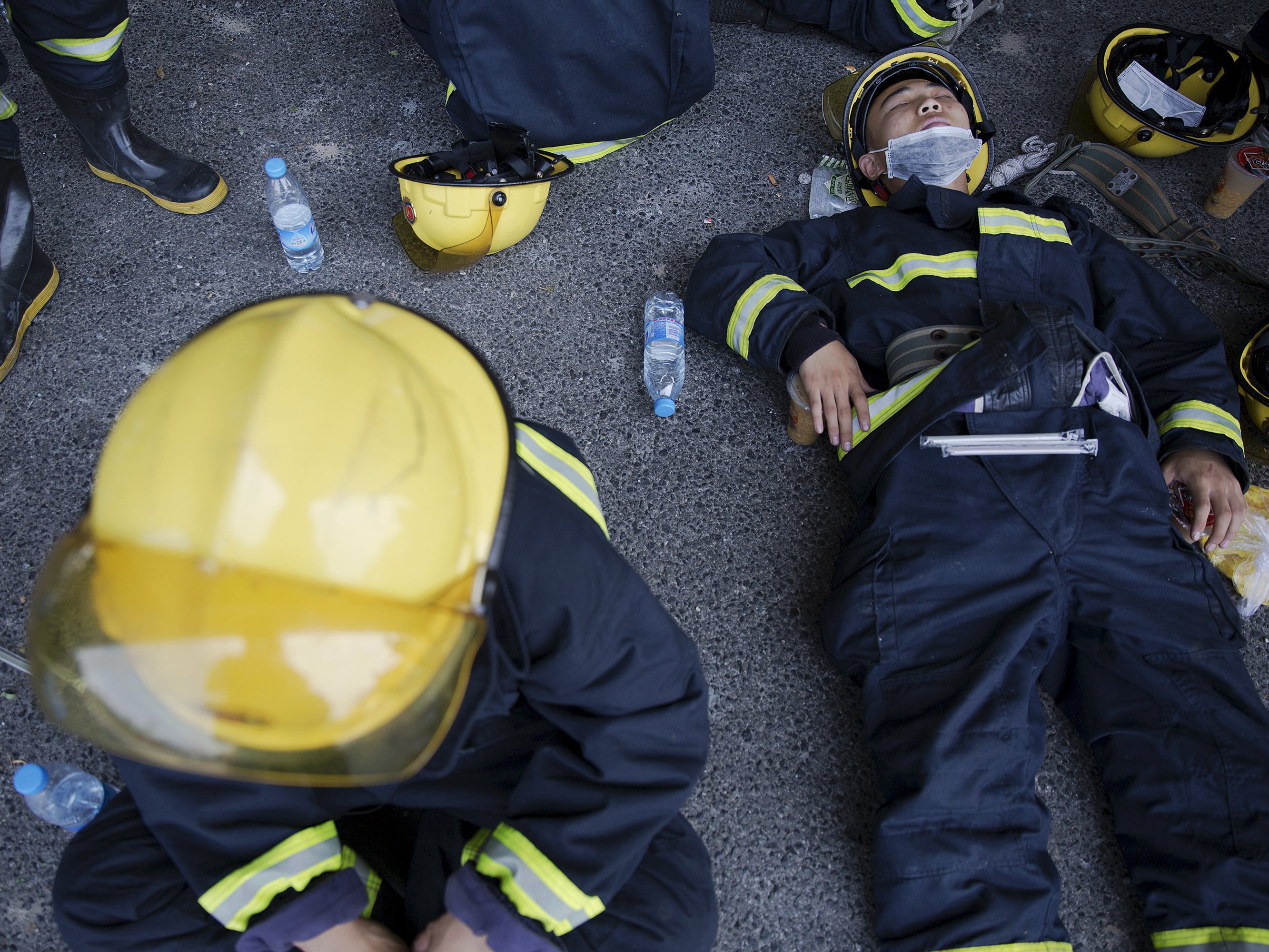 Firefighters take a break after trying to put fire down at the explosion site in Binhai new district in Tianjin,