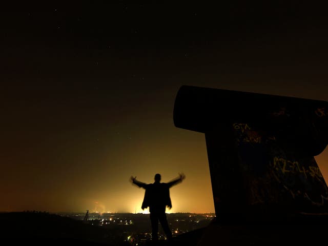 A man waits for the Perseid meteor shower at night on a mining dump in Gelsenkirchen, western Germany