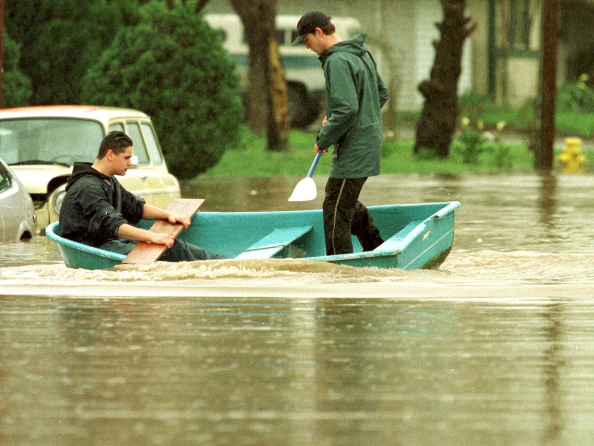 Jermey Vargas (L), and Jon Stanton paddle through their neighborhood street in Petaluma, California after El Niño struck in 1998