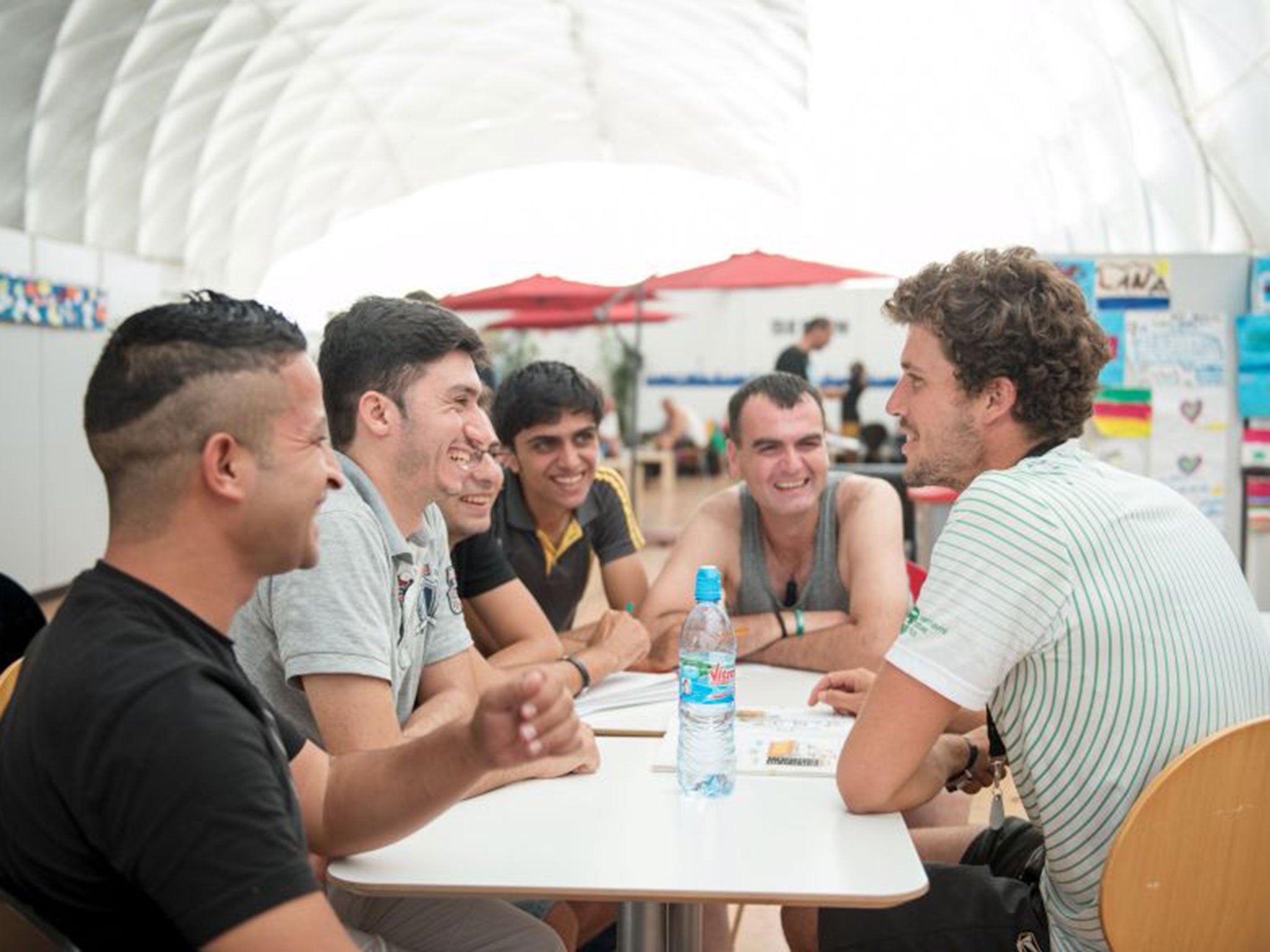 German trainee Adam (R) conducts a German lesson for migrants in an emergency accommodation shelter in a big air-inflated tent for asylum applicants in Berlin
