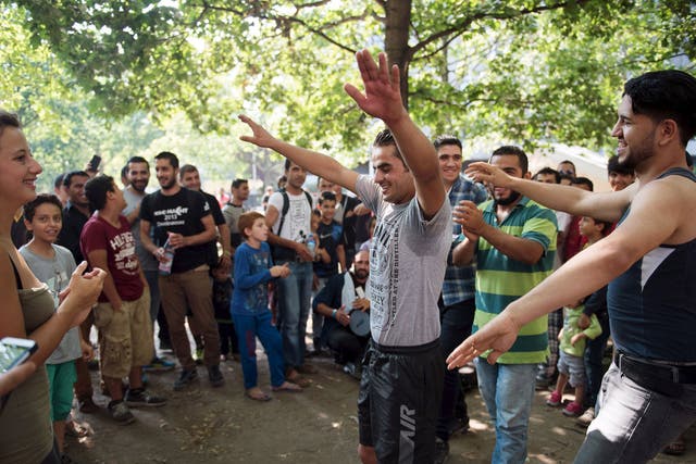 Volunteers play music with migrants and dance in front of the Berlin State Office for Health and Social Affairs where they wait with other migrants to apply for asylum in Berlin, August 10, 2015