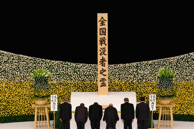 Relatives of the war dead add flowers to a bank of chrysanthemums in the Budokan Hall, Tokyo