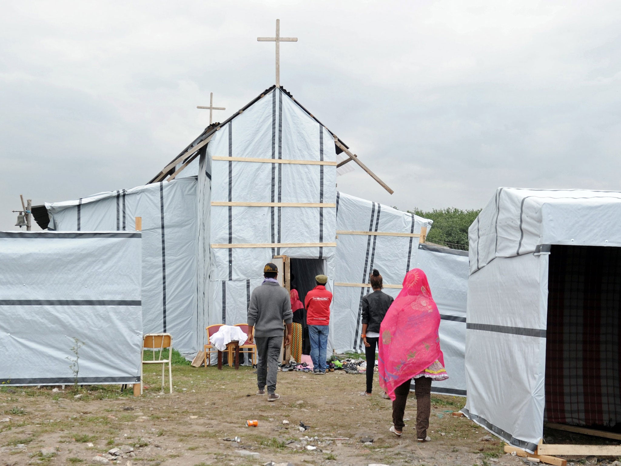 Migrants enter into the makeshift church built in the migrant camp called the 'new jungle' in Calais, near The Jungle.