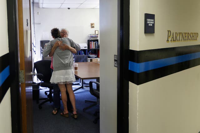 Volunteer Ruth Cote, facing, hugs a woman inside the police station in Gloucester