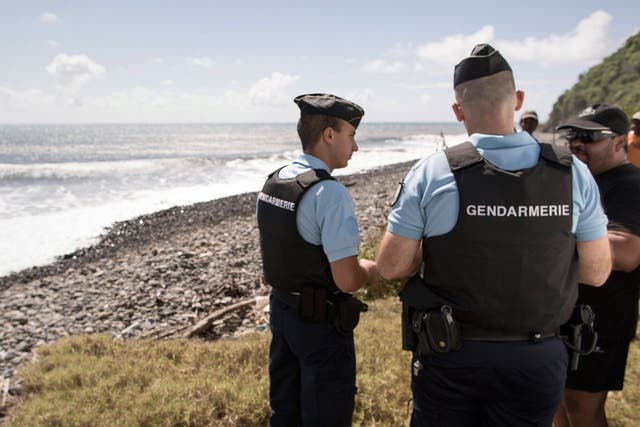 Police officers question workers who found debri on the coast of Sainte Suzanne, Reunion Island, France