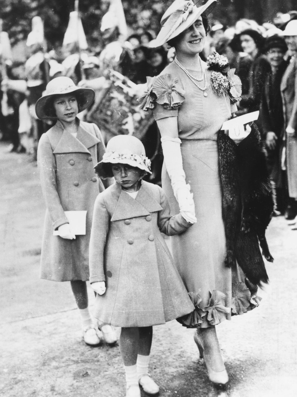 The nine-year-old Elizabeth attends an aristocratic wedding in 1936 with her mother and younger sister. Later in that year, with the death of her grandfather and the abdication of her Uncle Edward VIII, she became first in line to the throne