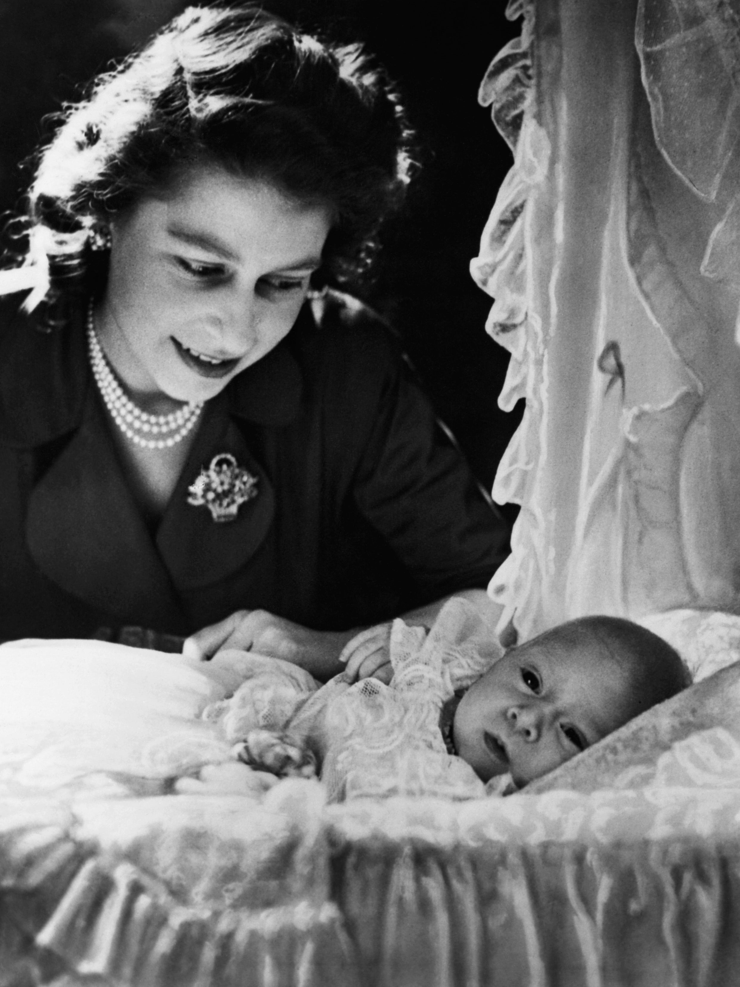 Elizabeth smiles at her first child, a month-old Prince Charles who was born on 14 November 1948