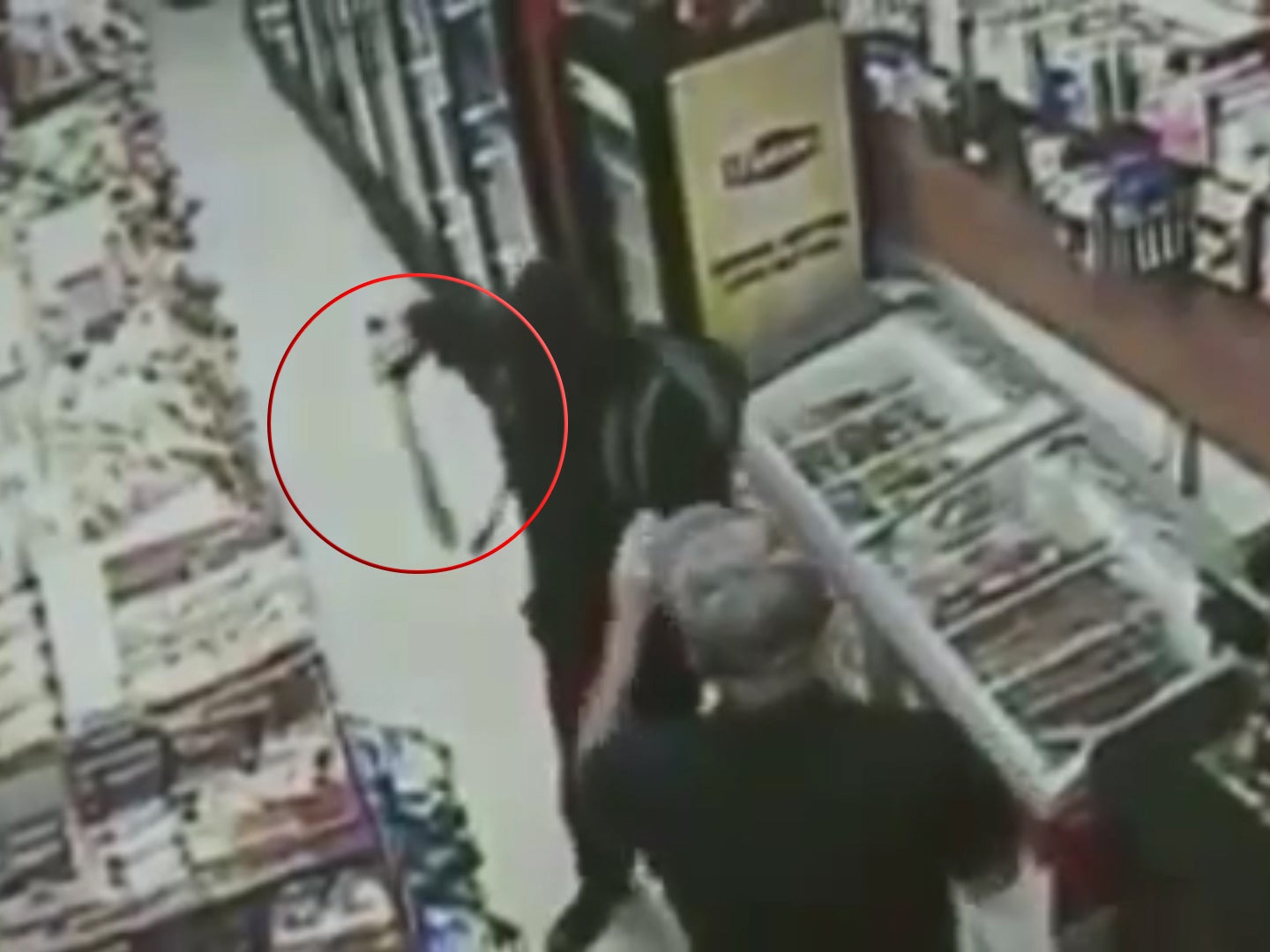 The masked robber wields their weapon at customer