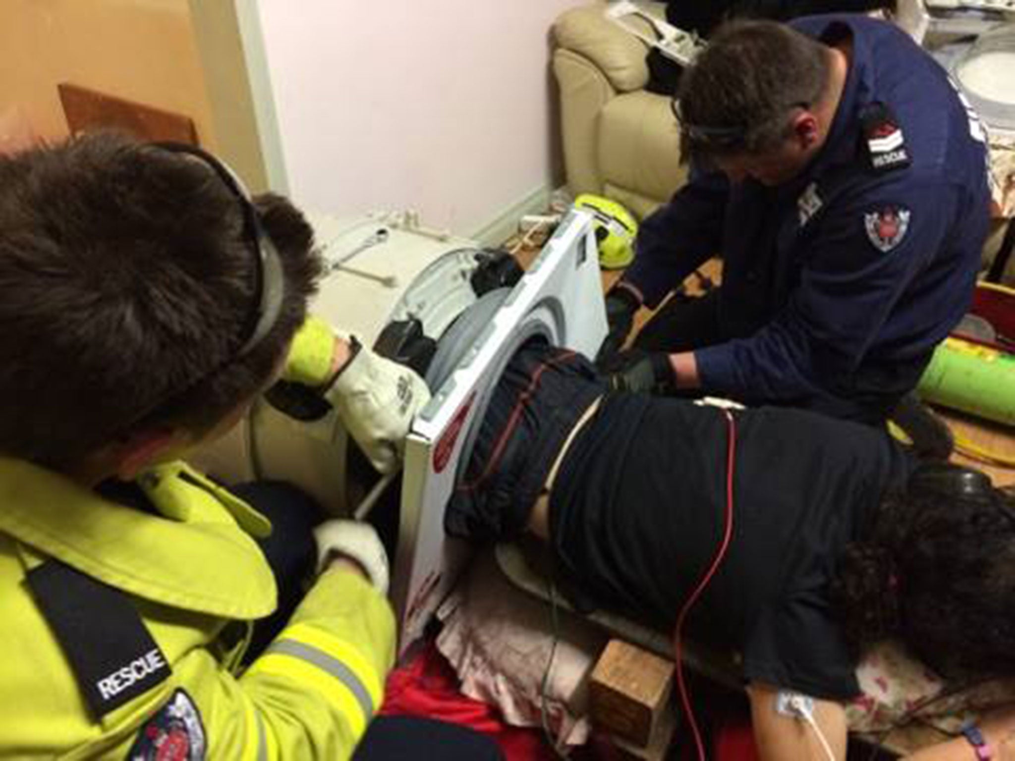 Firefighters work to free a man who got stuck in a washing machine