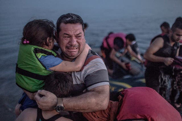 A Syrian father holds his children close as his arrives on the Greek Island of Kos