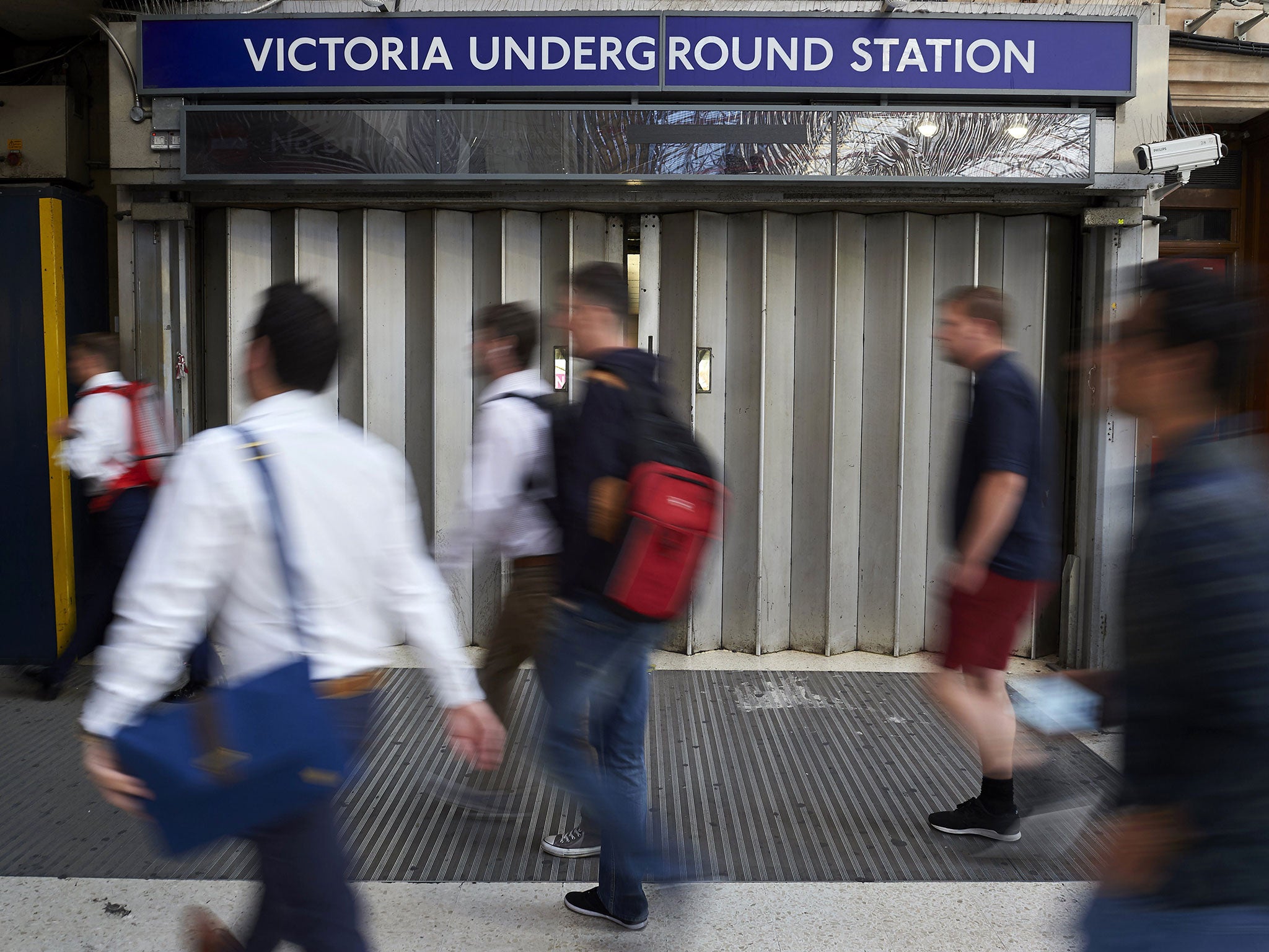 Early morning commuters walk past a closed underground gate at Victoria station during a tube strike in London on July 9, 2015. London's roads, buses and overland trains struggled to cope in Thursday's morning rush hour as commuters battled into work in the face of London Underground's first strike shutdown since 2002