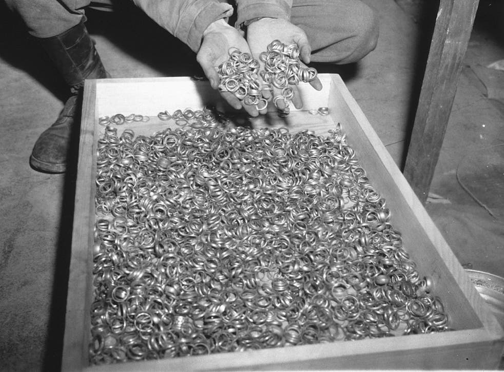 A US soldier inspects thousands of gold wedding rings taken from Jews by the Nazis and stashed in the Heilbron Salt Mines, in 1945 in Germany