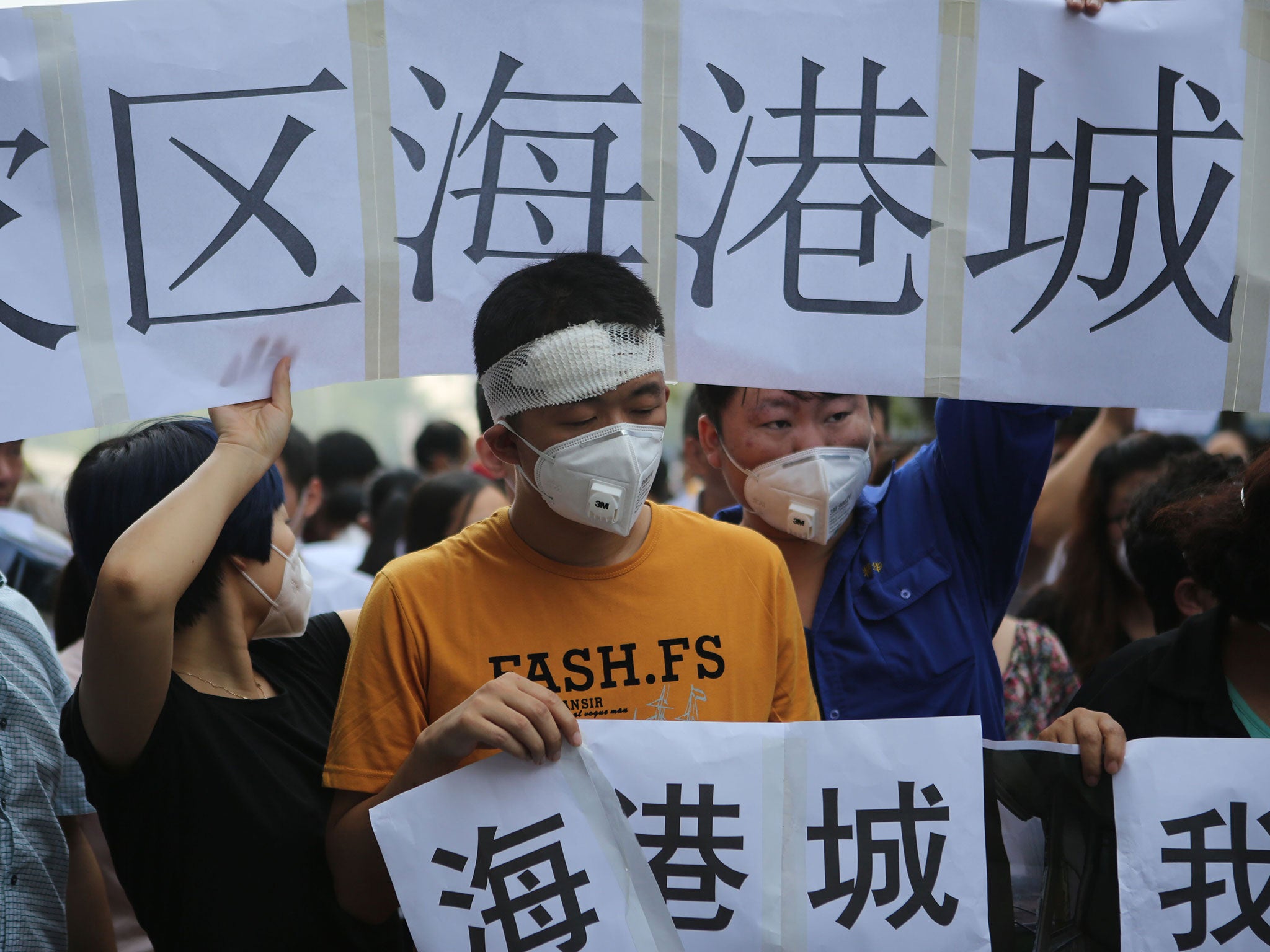 Residents affected by the explosions hold banners and placards as they protest outside the hotel where authorities are holding a press conferences