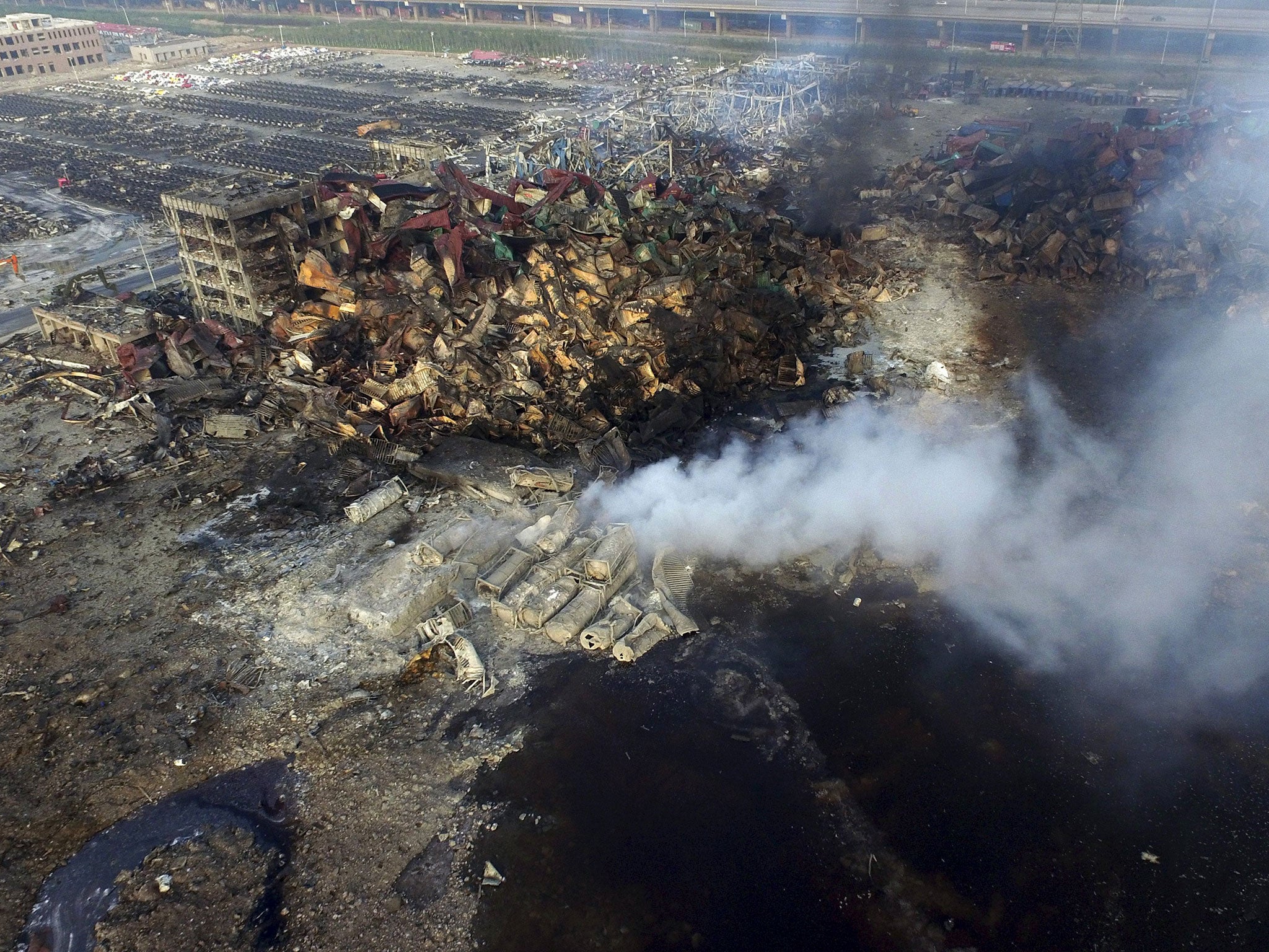 An aerial picture shows smoke rising from the debris among shipping containers at the site of the explosions at Binhai new district in Tianjin, China