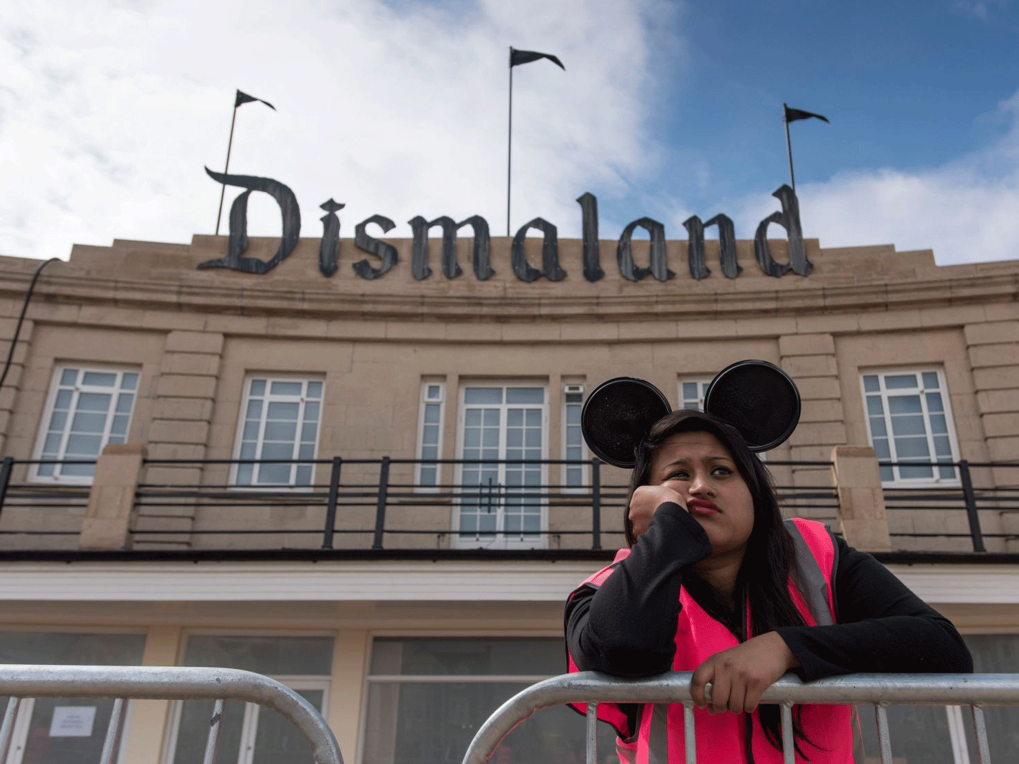 One of the park's trademark bored steward stands below the rusting Dismaland sign in Weston Super Mare