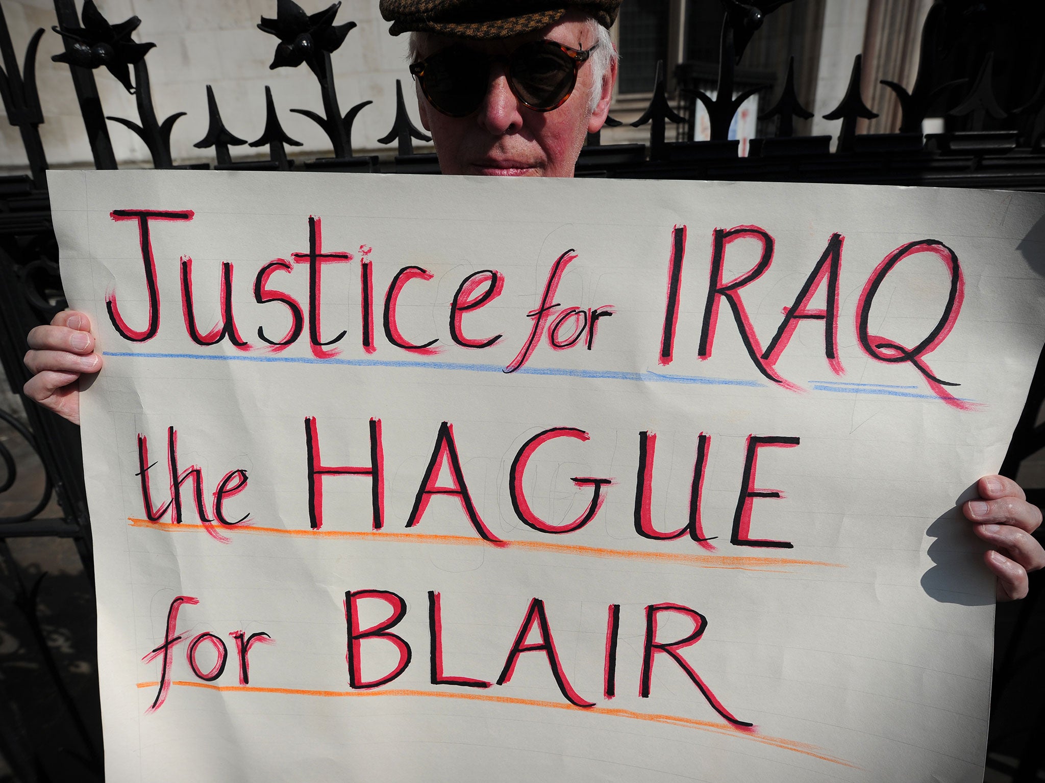 An anti-war protester holds a placard that reads 'Justice for Iraq, the Hague for Blair' during a demonstration outside the High Court in central London on May 28, 2012