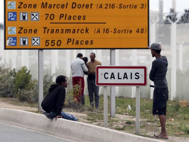 People stand near the side of the road in Calais, close to the large camp nearby