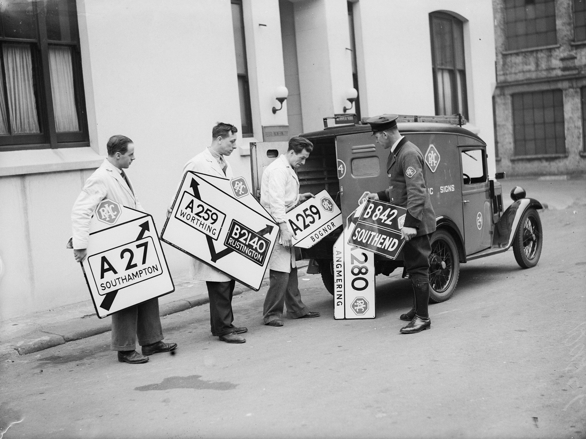 8th April 1936:  New roadsigns being loaded into a van at the RAC sign factory at Victoria, London.