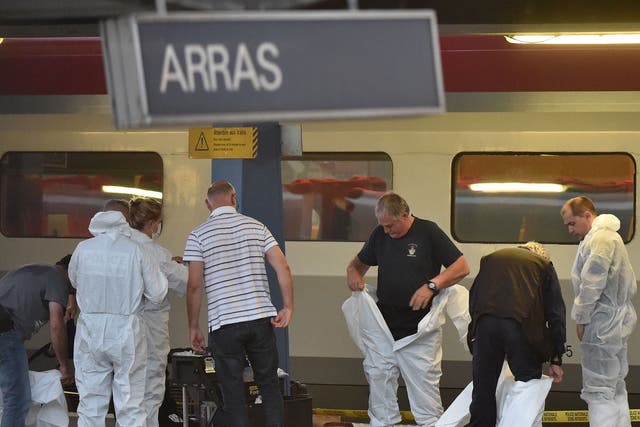Criminal and forensic investigators put on protective suits on a platform next to a train at the train station in Arras