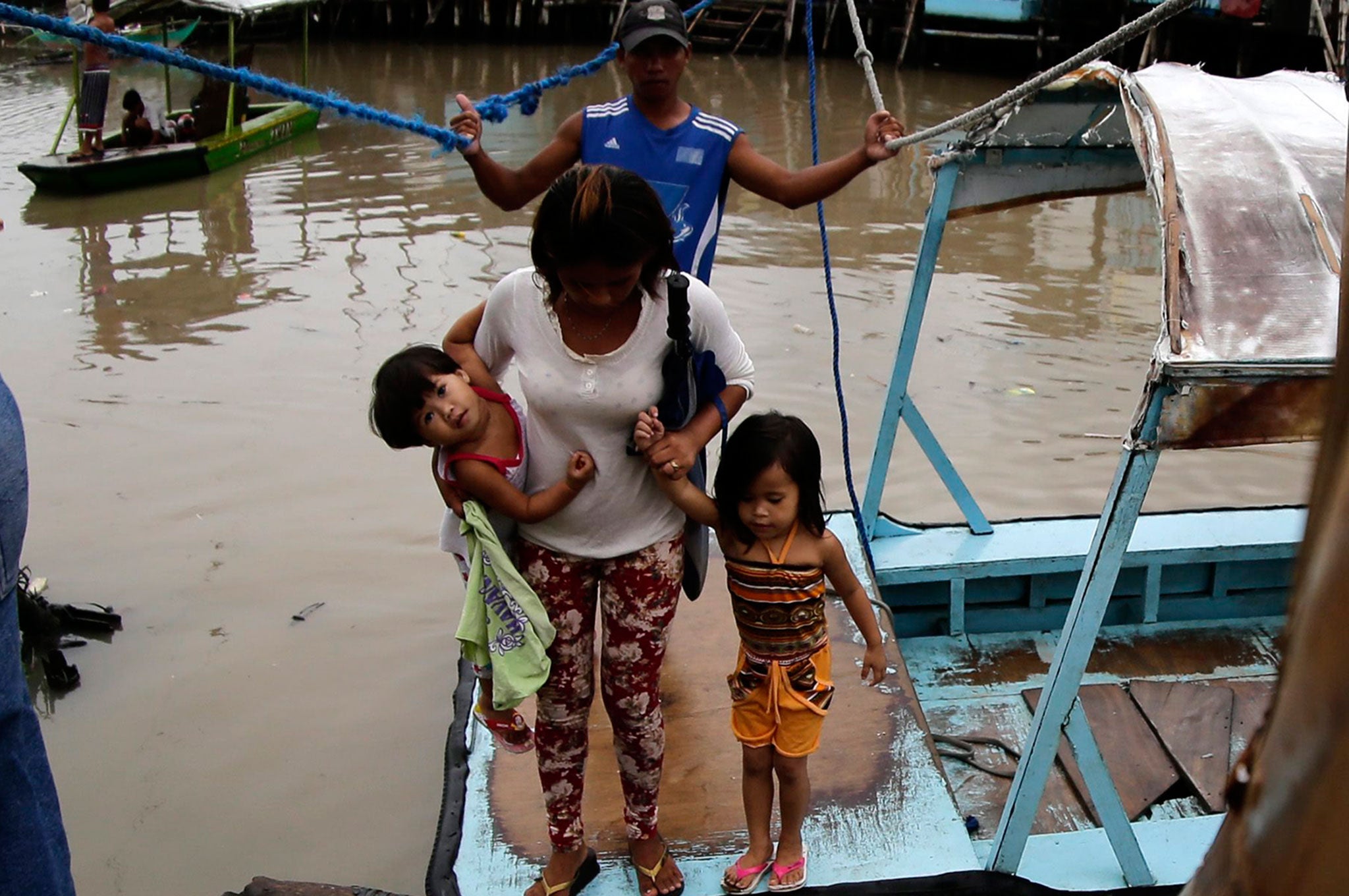 Filipino residents disembark from a makeshift boat at a swelling river in Las Pinas city, south of Manila, Philippines